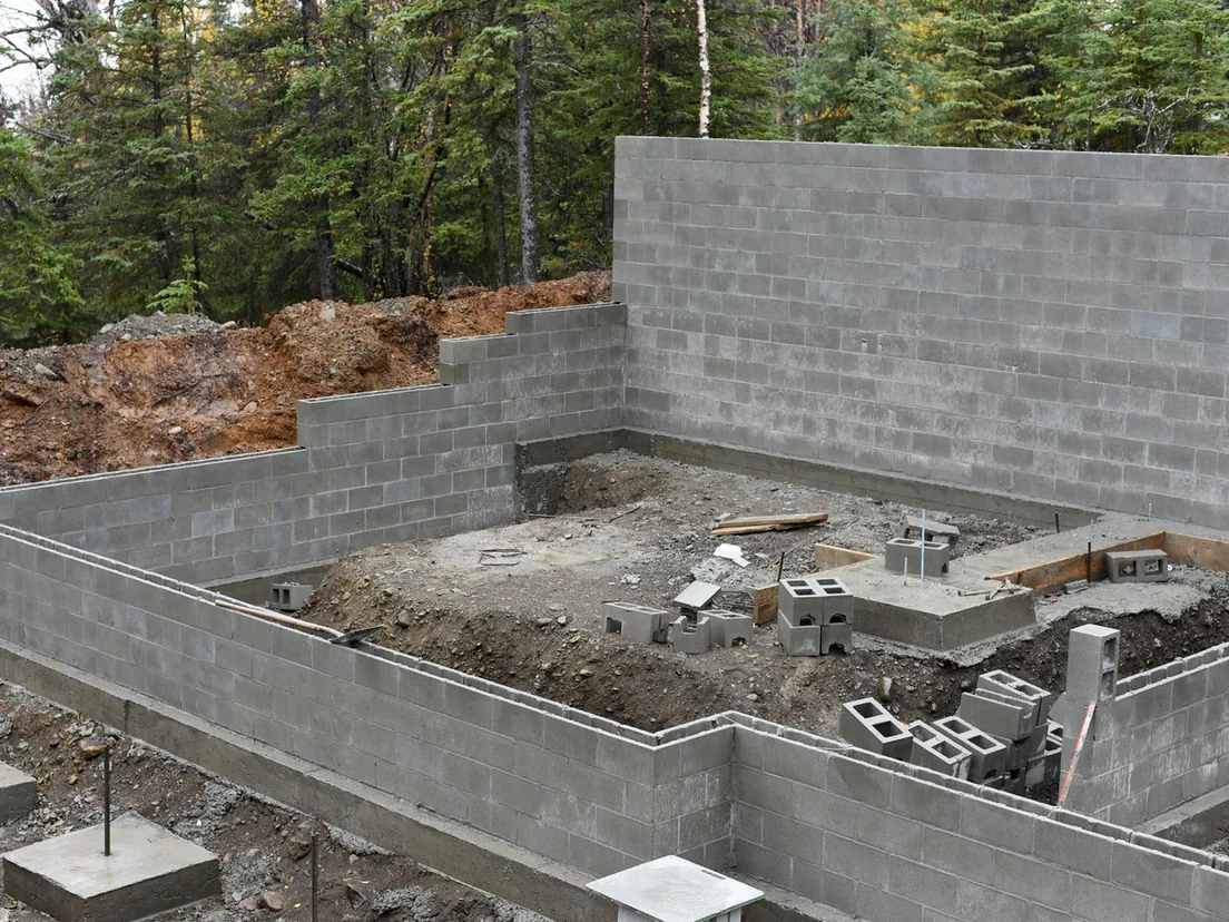 Concrete block foundation and basement walls on a wooded lot, block masonry