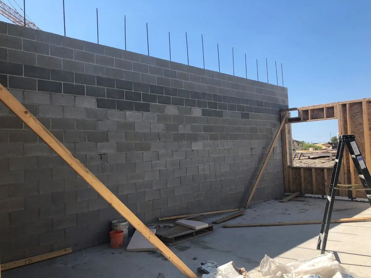 Tall concrete block wall braced with timber on a new building, block masonry
