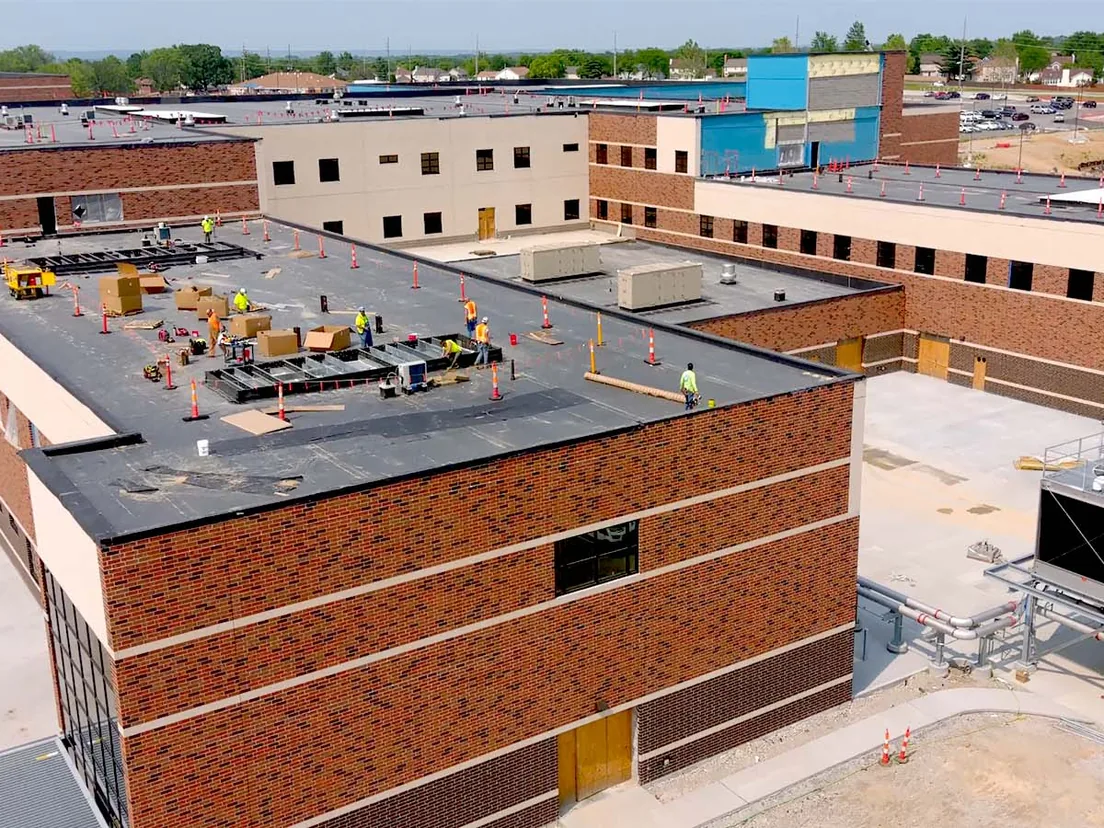 Aerial view of a new brick commercial building with roof work underway, brick veneer