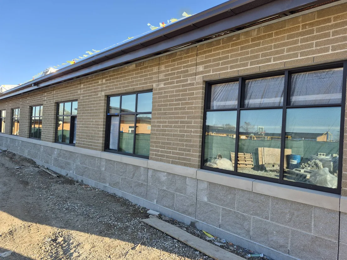 New commercial building with tan masonry walls over a split face concrete block base, commercial masonry