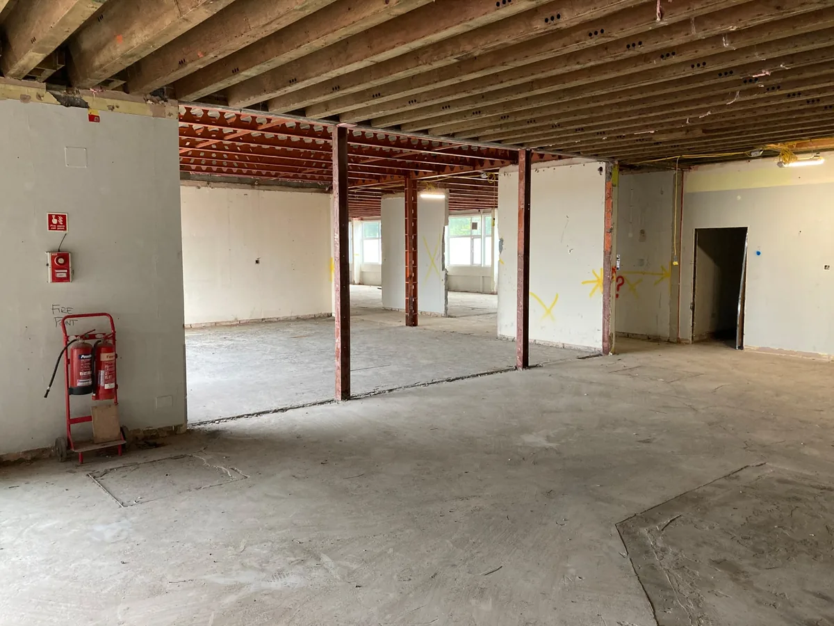 Commercial floor stripped to the timber joists and steel beams with a bare concrete floor, interior demolition